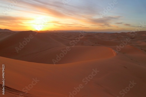 Sun at horizon in the sand dunes of Erg Chebbi desert during golden hour at sunset in Morcco