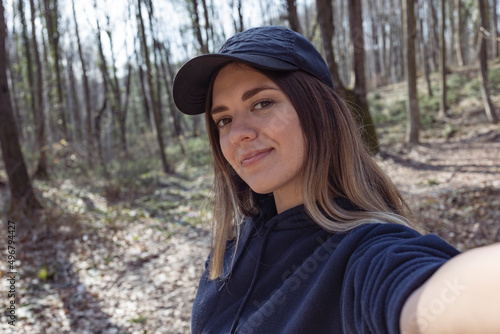 Beautiful girl with hat taking selfie in forest. She is so happy and smiling.