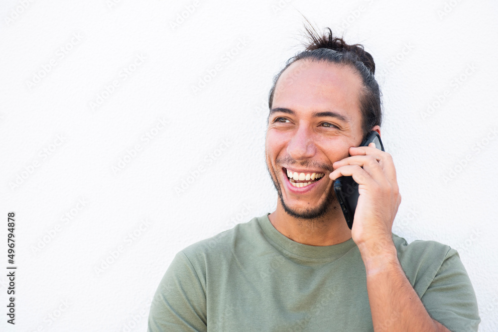 Happy man with pulled up hair bun talking on mobile phone over white background Happy man with pulled up hair bun talking on mobile phone over white background