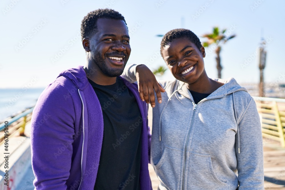 Man and woman couple wearing sportswear standing together at seaside Man and woman couple wearing sportswear standing together at seaside
