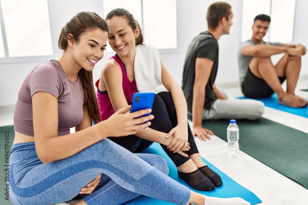 Group of young hispanic people smiling happy relaxing and using smartphone at sport center. Group of young hispanic people smiling happy relaxing and using smartphone at sport center.