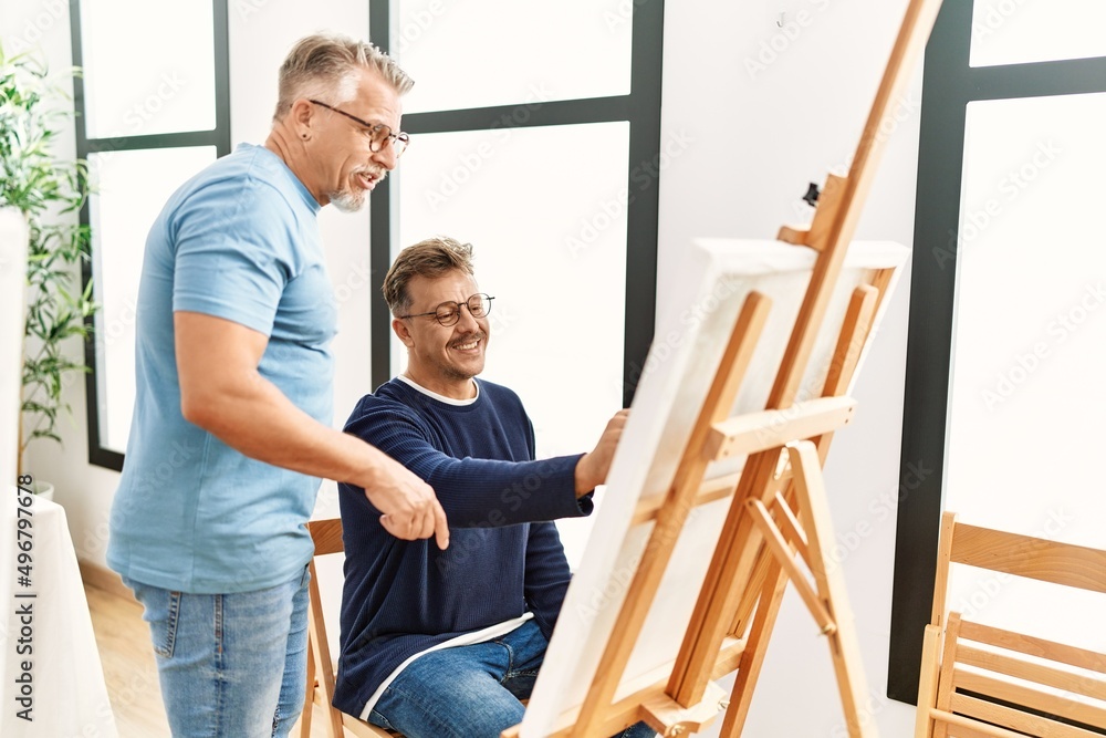 Middle age art teacher looking draw student at studio. Middle age art teacher looking draw student at studio.