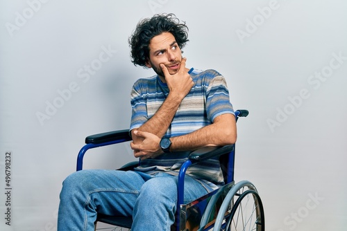 Handsome hispanic man sitting on wheelchair thinking worried about a question, concerned and nervous with hand on chin