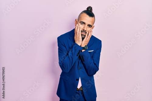 Young hispanic man wearing business suit and tie tired hands covering face, depression and sadness, upset and irritated for problem © Krakenimages.com