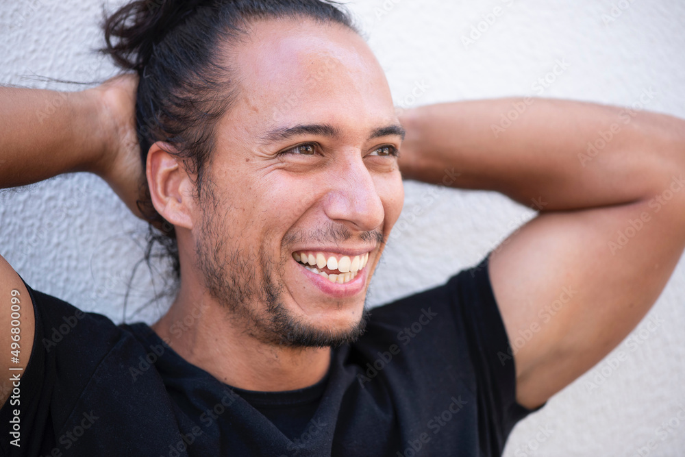 Cheerful man with pulled up hair bun and hands behind head over white background Cheerful man with pulled up hair bun and hands behind head over white background