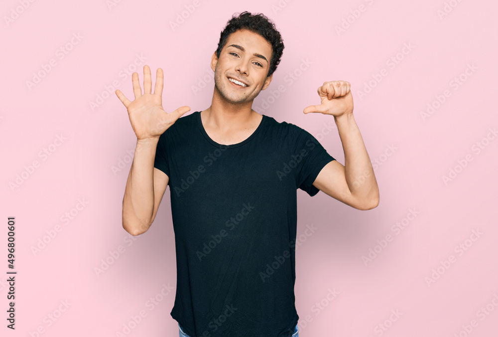 Young handsome man wearing casual black t shirt showing and pointing up with fingers number six while smiling confident and happy. Young handsome man wearing casual black t shirt showing and pointing up with fingers number six while smiling confident and happy.