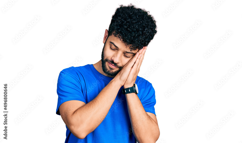 Young arab man with beard wearing casual blue t shirt sleeping tired dreaming and posing with hands together while smiling with closed eyes. Young arab man with beard wearing casual blue t shirt sleeping tired dreaming and posing with hands together while smiling with closed eyes.