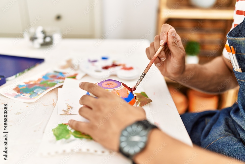 Young arab artist man smiling happy painting ceramic at art studio. Young arab artist man smiling happy painting ceramic at art studio.