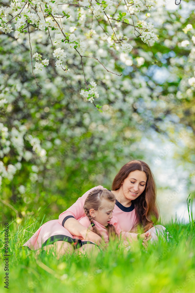 mother and daughter in identical dresses lie in the grass mother and daughter in identical dresses lie in the grass