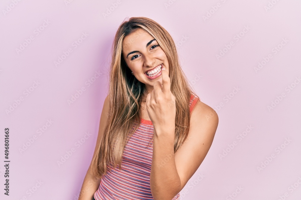 Beautiful hispanic woman wearing casual summer t shirt beckoning come here gesture with hand inviting welcoming happy and smiling Beautiful hispanic woman wearing casual summer t shirt beckoning come here gesture with hand inviting welcoming happy and smiling