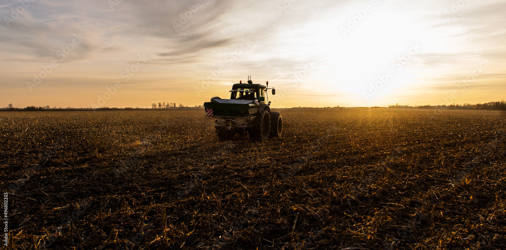 Fototapeta premium Tractor spreading artificial fertilizers in field