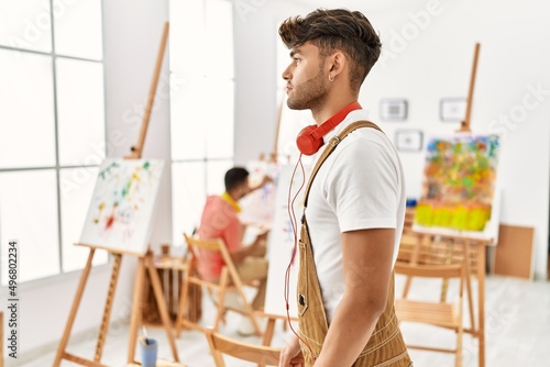 Young hispanic man at art studio looking to side, relax profile pose with natural face with confident smile.
