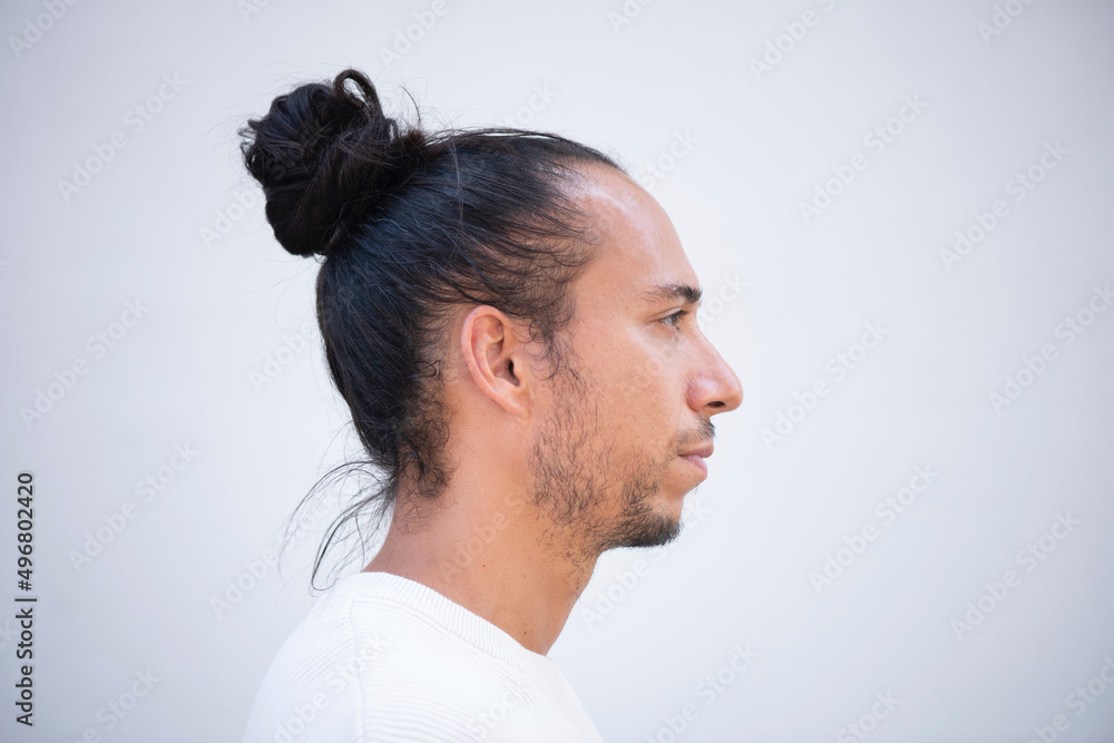 Fototapeta premium Profile face of man with pulled up hair bun over white background