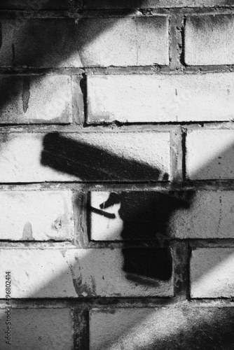 Vertical closeup shot of a gun graffiti on a brick wall  on a grayscale
