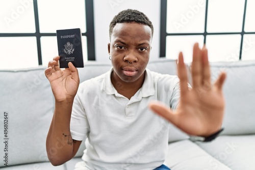 Young african man holding united states passport with open hand doing stop sign with serious and confident expression, defense gesture © Krakenimages.com