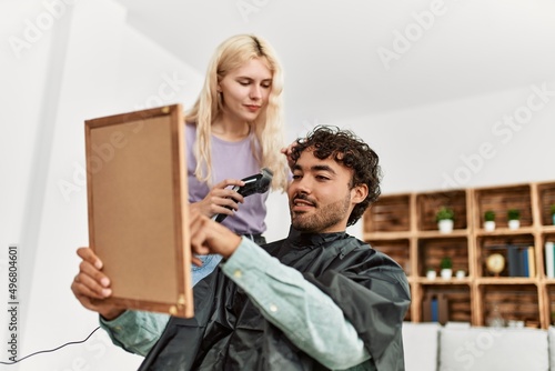 Young woman cutting hair to her boyfriend at home.