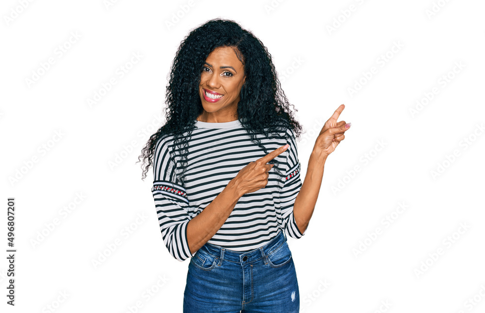 Middle age african american woman wearing casual clothes smiling and looking at the camera pointing with two hands and fingers to the side. Middle age african american woman wearing casual clothes smiling and looking at the camera pointing with two hands and fingers to the side.