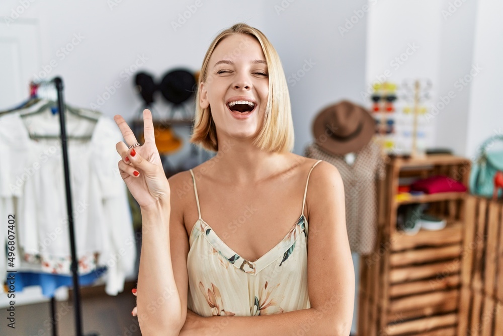 Young caucasian woman at retail shop smiling with happy face winking at the camera doing victory sign. number two. Young caucasian woman at retail shop smiling with happy face winking at the camera doing victory sign. number two.