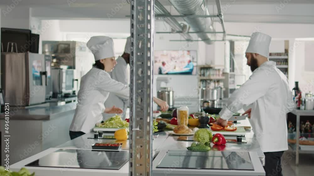 Team of cooks slicing vegetables on cutting board for meal preparation in restaurant kitchen. Man and woman cooking gourmet food dish with organic ingredients, working on culinary recipe. Team of cooks slicing vegetables on cutting board for meal preparation in restaurant kitchen. Man and woman cooking gourmet food dish with organic ingredients, working on culinary recipe.