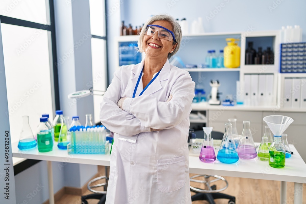 Middle age woman wearing scientist uniform standing with arms crossed gesture at laboratory Middle age woman wearing scientist uniform standing with arms crossed gesture at laboratory