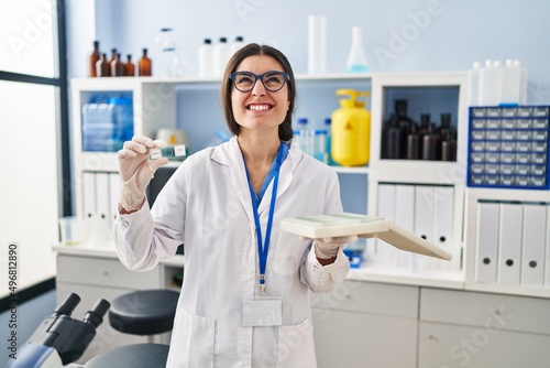 Young hispanic woman working at scientist laboratory with blood samples angry and mad screaming frustrated and furious  shouting with anger looking up.
