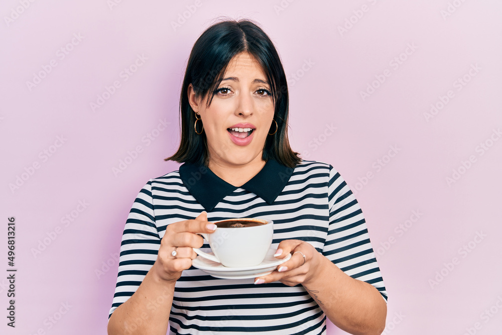 Young hispanic woman drinking a cup of coffee clueless and confused expression. doubt concept. Young hispanic woman drinking a cup of coffee clueless and confused expression. doubt concept.