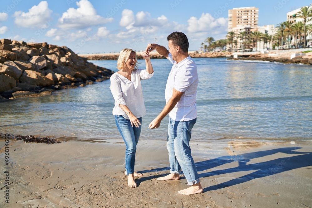 Middle age man and woman couple smiling confident dancing at seaside Middle age man and woman couple smiling confident dancing at seaside