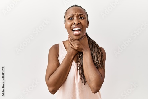 Black woman with braids standing over isolated background shouting and suffocate because painful strangle. health problem. asphyxiate and suicide concept.