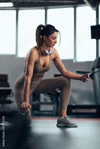 Pretty woman working out in a gym, making a pause. Adult pretty sporty lady with beautiful shaped body.