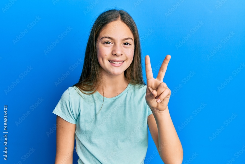 Beautiful brunette little girl wearing casual white t shirt showing and pointing up with fingers number two while smiling confident and happy. Beautiful brunette little girl wearing casual white t shirt showing and pointing up with fingers number two while smiling confident and happy.