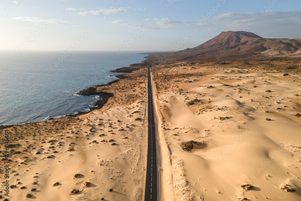 Aerial view of a road along the coast crossing the Sand Dune Natural Park in Corralejo, Fuerteventura, Canary Islands, Spain. Aerial view of a road along the coast crossing the Sand Dune Natural Park in Corralejo, Fuerteventura, Canary Islands, Spain.
