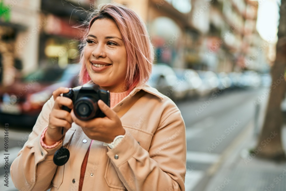 Young hispanic girl smiling happy using reflex camera at the city.