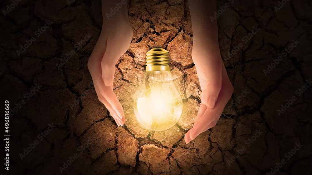 Glowing Lightbulb on Drought Earth with Hand Caring it .Lamp Lighting