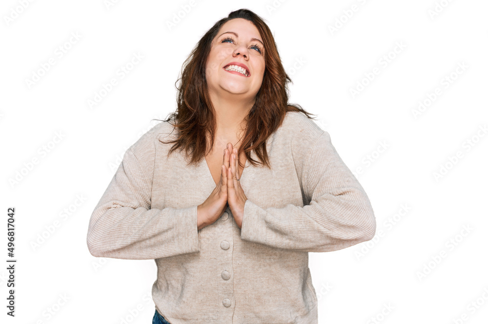 Young plus size woman wearing casual clothes begging and praying with hands together with hope expression on face very emotional and worried. begging. Young plus size woman wearing casual clothes begging and praying with hands together with hope expression on face very emotional and worried. begging.