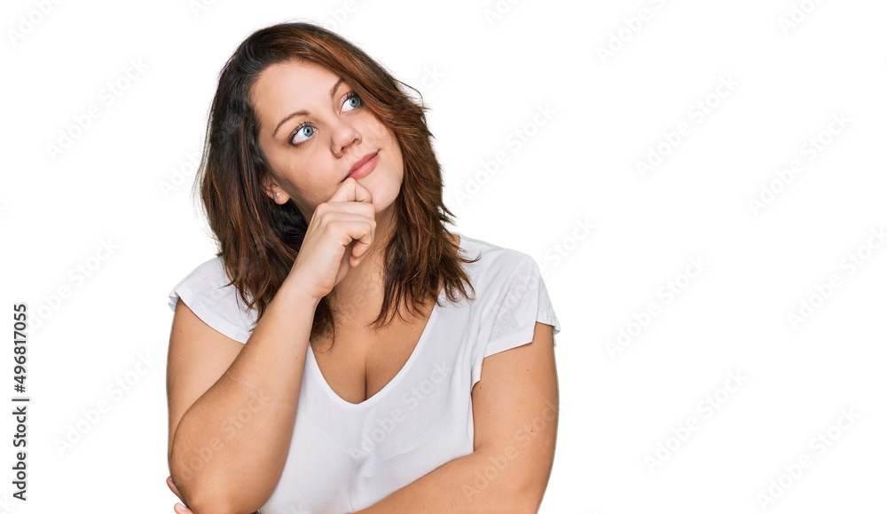 Young plus size woman wearing casual white t shirt with hand on chin thinking about question, pensive expression. smiling with thoughtful face. doubt concept. Young plus size woman wearing casual white t shirt with hand on chin thinking about question, pensive expression. smiling with thoughtful face. doubt concept.