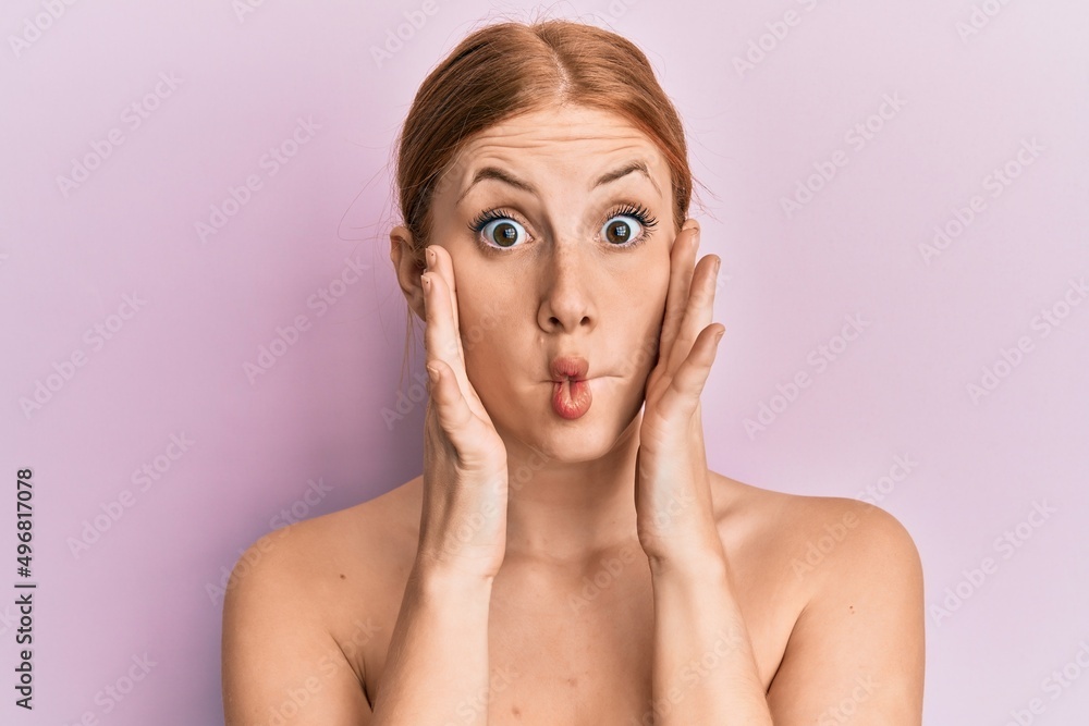 Young irish woman standing topless stretching skin face with hands making fish face with mouth and squinting eyes, crazy and comical. Young irish woman standing topless stretching skin face with hands making fish face with mouth and squinting eyes, crazy and comical.