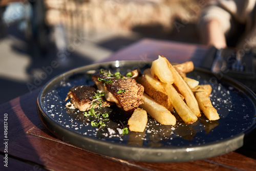  A plate of fish and chips potatoes on wooden surface photo