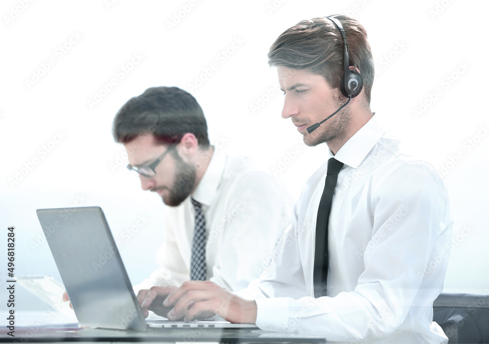 Manager with the headset uses a laptop to work with the client Manager with the headset uses a laptop to work with the client