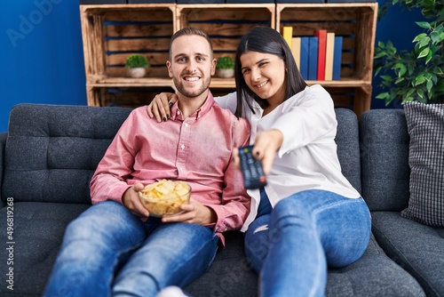 Man and woman couple watching movie sitting on sofa at home