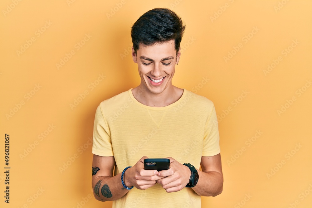 Young hispanic man using smartphone typing message smiling with a happy and cool smile on face. showing teeth. Young hispanic man using smartphone typing message smiling with a happy and cool smile on face. showing teeth.