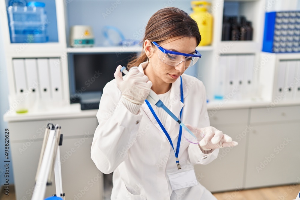 Young hispanic woman wearing scientist uniform using pipette at laboratory Young hispanic woman wearing scientist uniform using pipette at laboratory