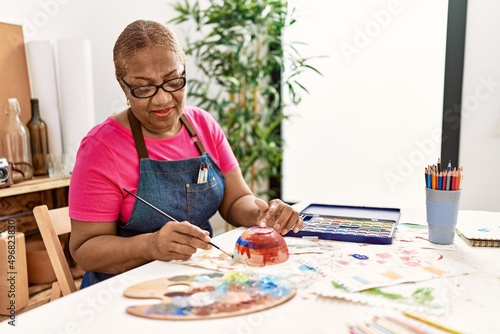 Senior african american woman smiling confident painting clay ceramic at art studio