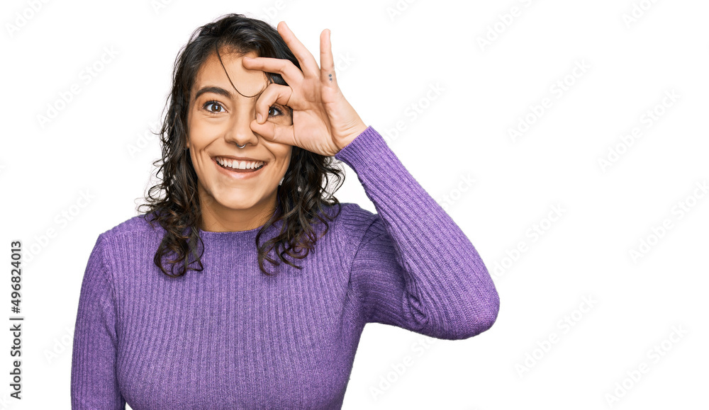 Young hispanic woman wearing casual clothes doing ok gesture with hand smiling, eye looking through fingers with happy face. Young hispanic woman wearing casual clothes doing ok gesture with hand smiling, eye looking through fingers with happy face.