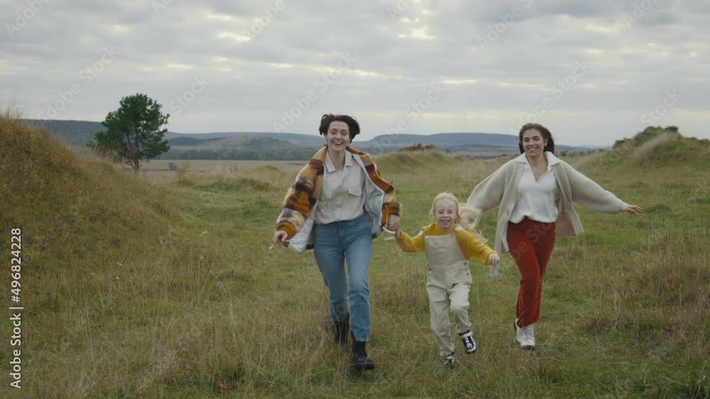 Cheerful lgbt family of three running and smiling outdoors Cheerful lgbt family of three running and smiling outdoors