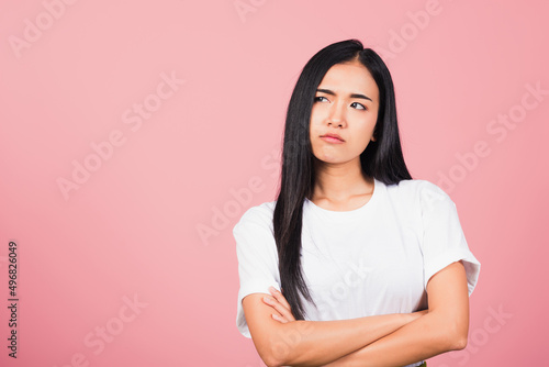 Asian happy portrait beautiful cute young woman standing with crossed arms angry and mad raising fist frustrated and furious while shouting with anger isolated, studio shot on pink background