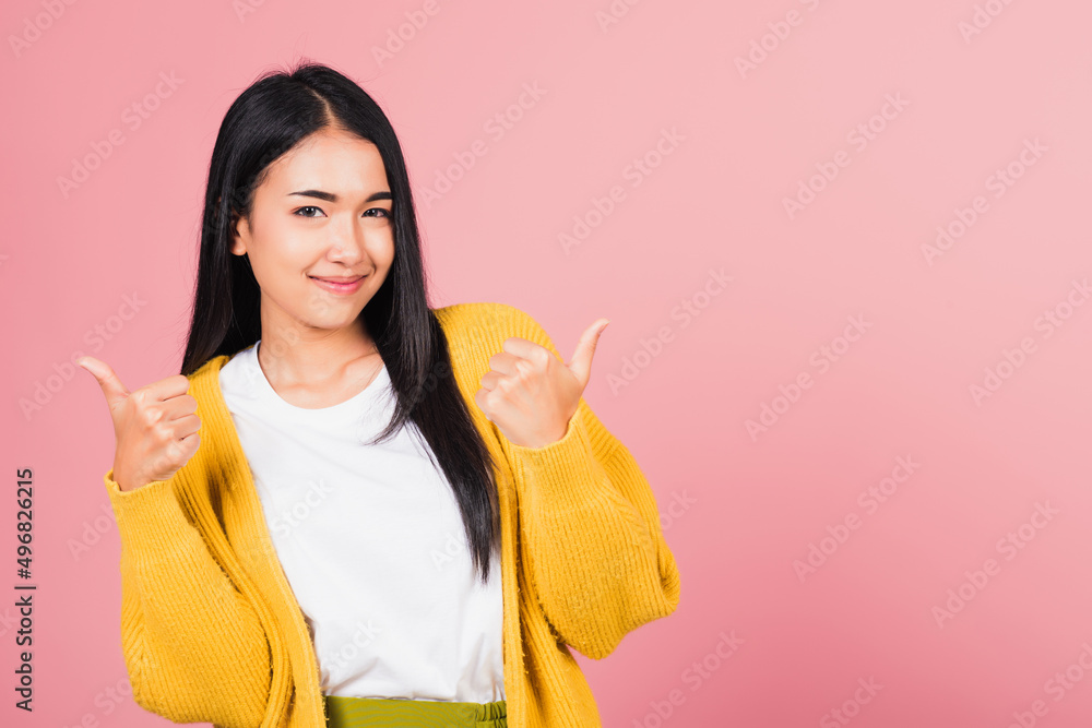 .Portrait Asian beautiful young woman smile she standing made finger thumbs up, Ok sign to agree studio shot isolated on pink background, Thai female successful like finger gesture with copy space .Portrait Asian beautiful young woman smile she standing made finger thumbs up, Ok sign to agree studio shot isolated on pink background, Thai female successful like finger gesture with copy space