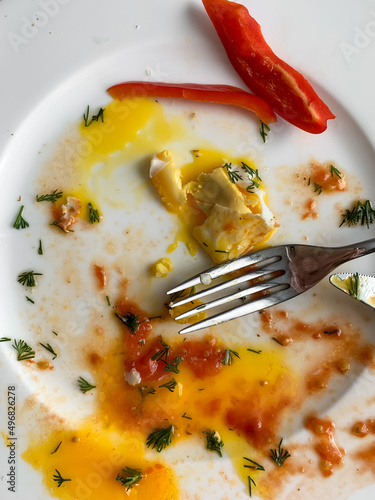 A dirty plate with leftovers and a fork