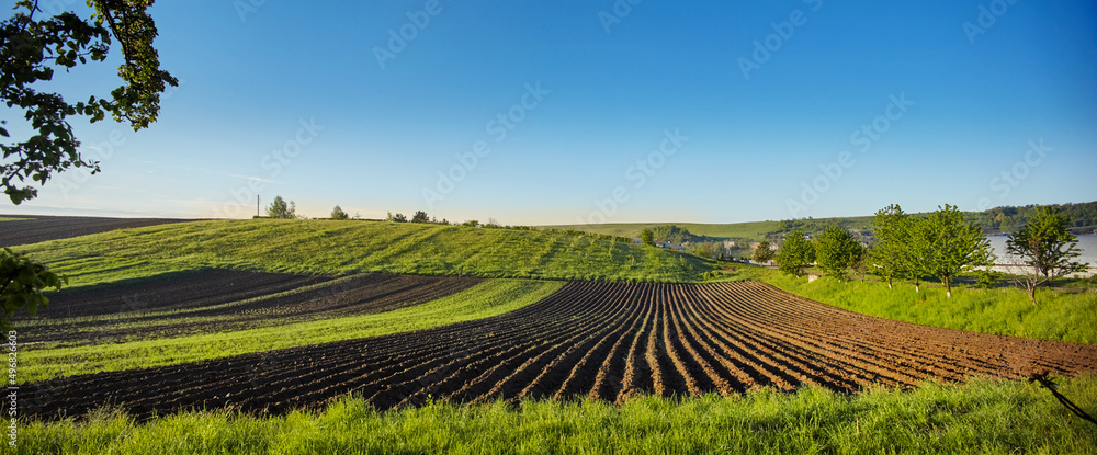 Spring Landscape with Plowed Field on the Background of Beautiful Blue Sky. Ploughed Soil. Agriculture Concept. Copy Space.