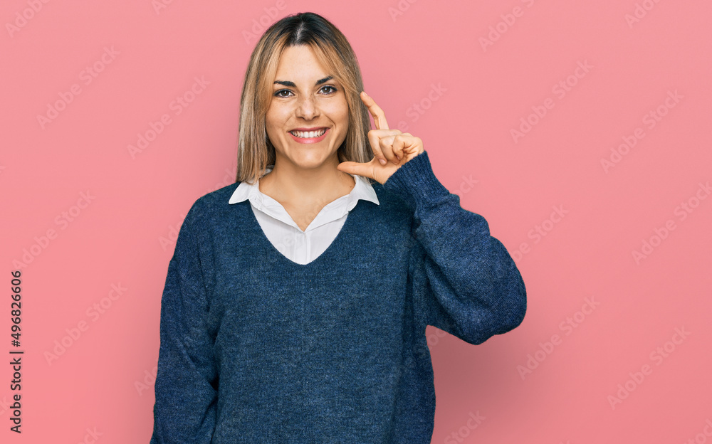 Young caucasian woman wearing casual clothes smiling and confident gesturing with hand doing small size sign with fingers looking and the camera. measure concept. Young caucasian woman wearing casual clothes smiling and confident gesturing with hand doing small size sign with fingers looking and the camera. measure concept.