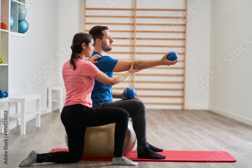 a young woman instructing a man on the correct posture for exercising